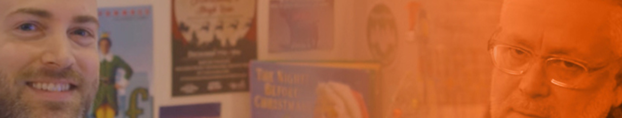 Image of two people sitting in a cubile one with an annoyed expression. The other with a smile.