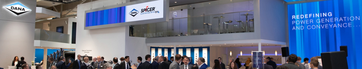 A large group of tradeshow attendees mingle among branded booths with a large Dana and Spicer booth as the focal point.