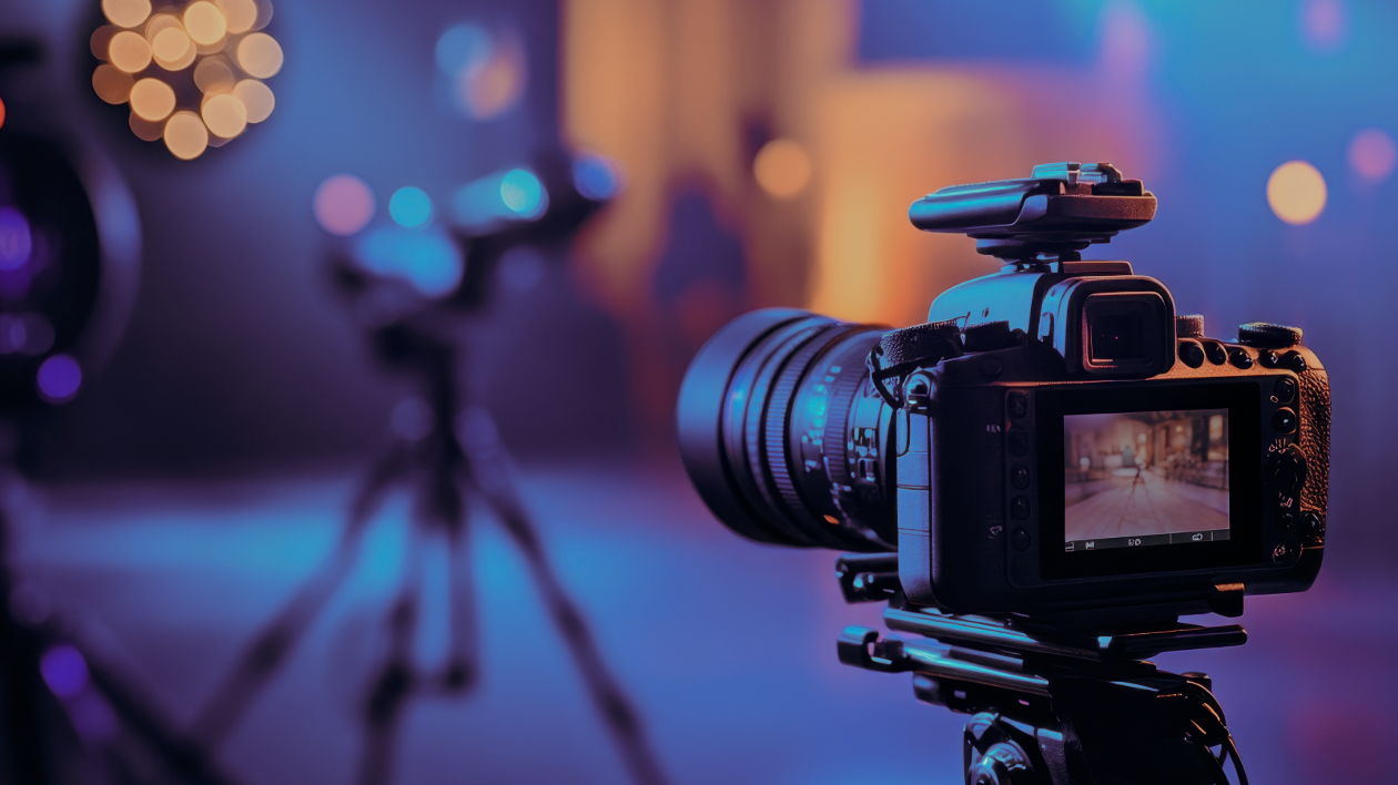 A camera is seen in the foreground as it captures an event or scene off-screen