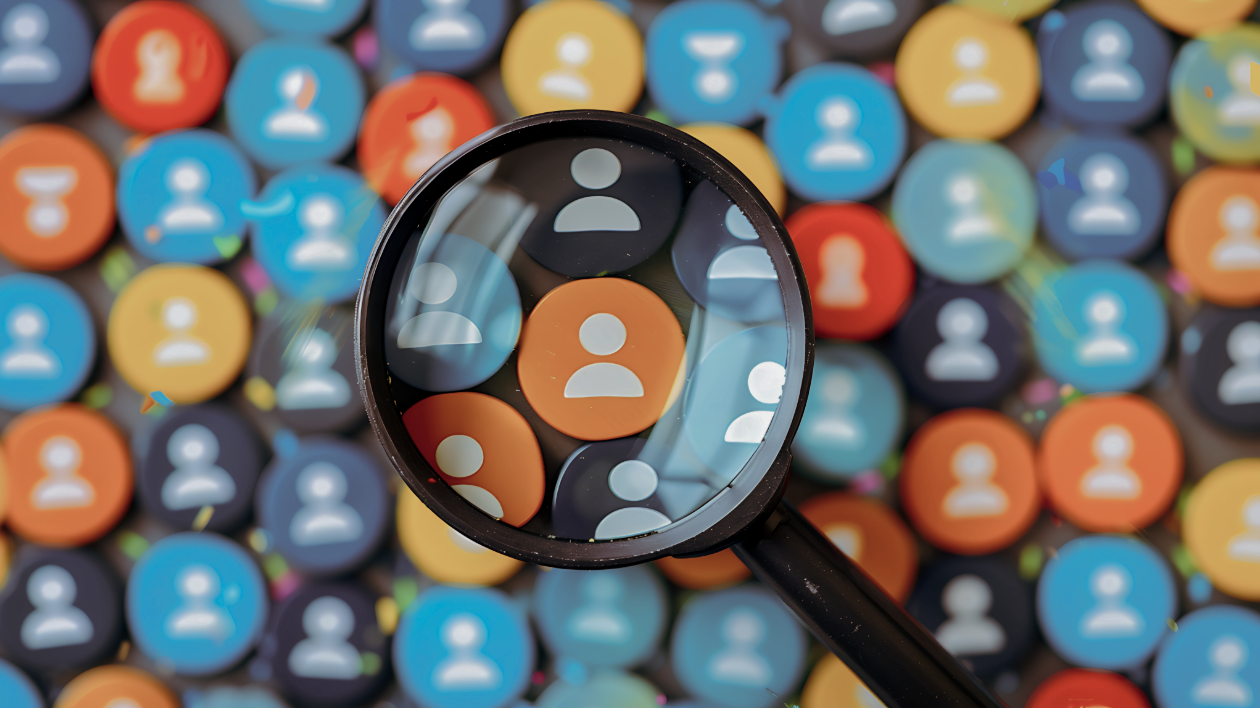 A magnifying glass hovers over a scattering of icons representing users.