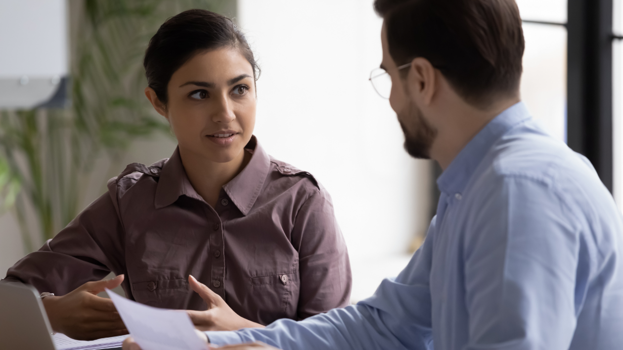A pair of teammates collaborate and brainstorm animatedly at a desk