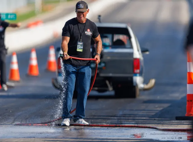 man-watering-drag-strip