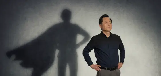 Image of a man satnding like a superhero, with a cape silhouette.